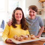Friends smiling while baking cupcakes together in a kitchen